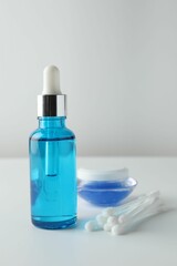 Bottle of chemical peel liquid, jar and cotton swabs on light background. Peeling procedure