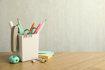 Stapler, holder and other different stationery on wooden table, space for text