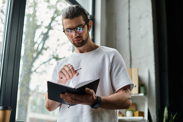 Caucasian businessman in white T-shirt writing on notebook.
