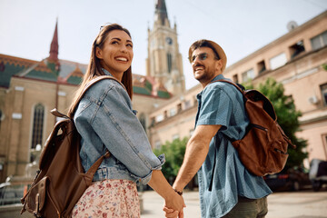 Young couple of travelers holding hands while walking through  town.