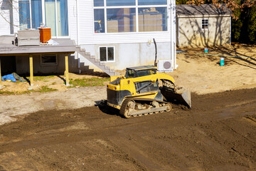 Tractor levels ground during construction work in backyard as part of an earthmoving job