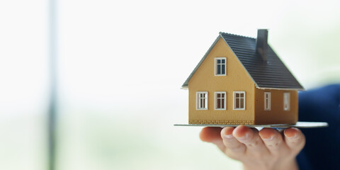 Close up real estate agent holding small house model, Home loan.