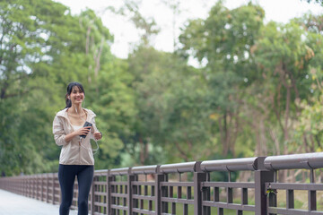 athlete asian woman wearing earphone using smartphone while workout at outdoor.