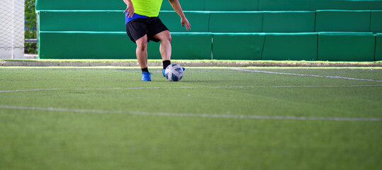Fototapeta premium Soccer players in action during a game on a grass field, focusing on their legs and the ball.