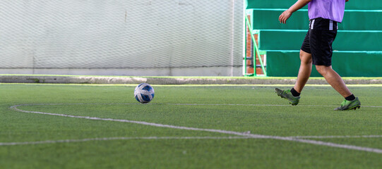 Soccer players in action during a game on a grass field, focusing on their legs and the ball.