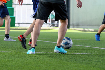 Soccer players in action during a game on a grass field, focusing on their legs and the ball.