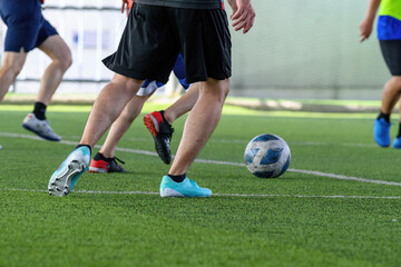 Soccer players in action during a game on a grass field, focusing on their legs and the ball.