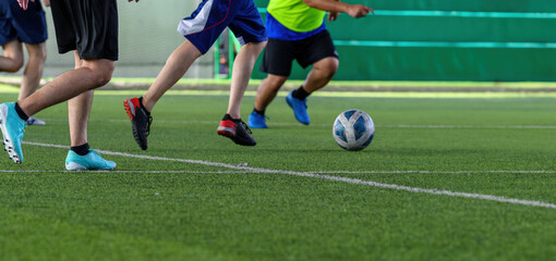 Soccer players in action during a game on a grass field, focusing on their legs and the ball.