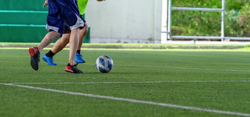 Soccer players in action during a game on a grass field, focusing on their legs and the ball.
