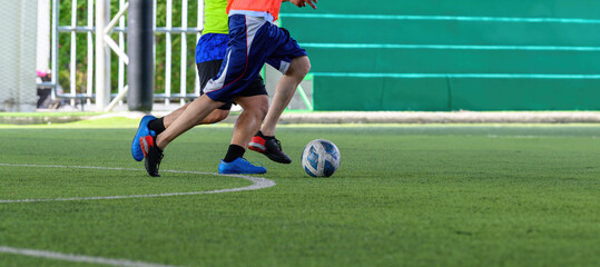 Obraz premium Soccer players in action during a game on a grass field, focusing on their legs and the ball.