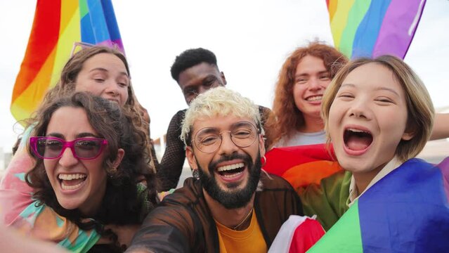 Selfie portrait of a group of lgbt mixed friends celebrating the gay pride parade with the rainbow flag. Multiracial lgtbi people having fun, smiling and looking at camera. Respect the sexuality