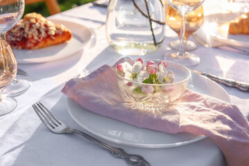Stylish table setting with beautiful spring flowers in garden