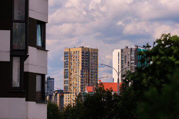 Naklejka premium Cityscape on a summer day, modern buildings and houses against the blue sky 