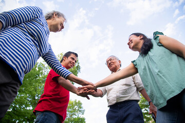 A  family of four is playing on a cloudy day, holding hands in a circle. 