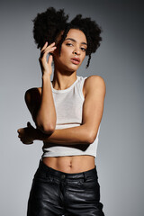 A young African American woman in a white tank top poses with a confident expression.