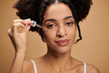 Obraz premium A young African American woman applies facial serum to her skin.
