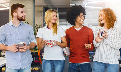 A gathering of individuals standing closely aligned in a row, facing forward, engaged in conversation or awaiting further instructions while drinking coffee