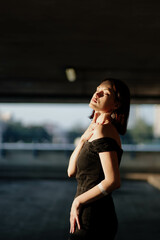 Obraz premium sexy woman in a black dress in the city in the sunlight.