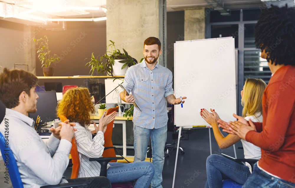 Poster a man stands in front of a group of attentive individuals, gesturing and speaking confidently as he 