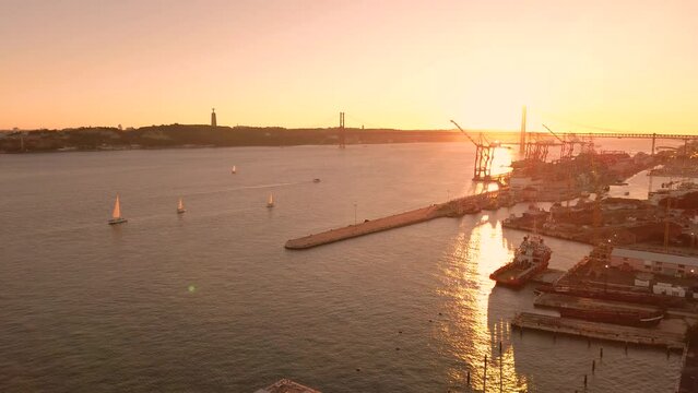 A cinematic aerial view of the Tagus River with sailing boats during a beautiful soft sunset. Lisbon, Portugal. High quality 4K footage. The drone hovered in one place, the camera motionless