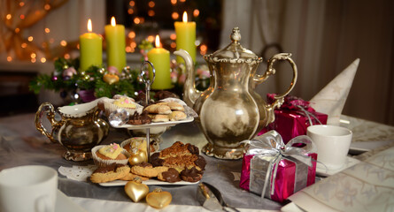 Coffee table set for Christmas. Silver coffee pot, Advent wreath, different home baked christmas cookies on an etagere and small gifts on the table.