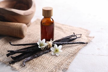 Vanilla pods, essential oil and flowers on light gray table