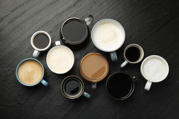 Different coffee drinks in cups on dark textured table, flat lay