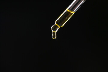 Dripping tincture from pipette on black background, closeup. Space for text