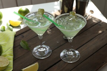 Delicious Margarita cocktail in glasses and lime on wooden table, closeup