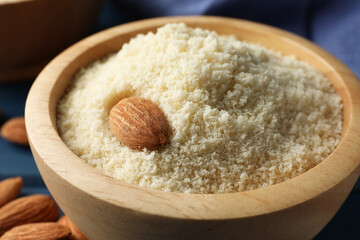 Fresh almond flour and nut in bowl on table, closeup