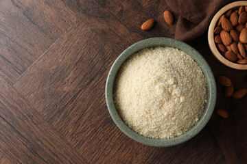 Fresh almond flour and nuts on wooden table, flat lay. Space for text