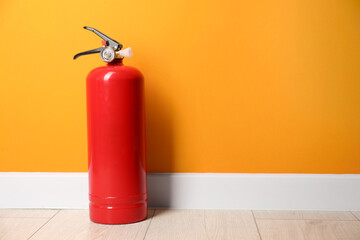 Fire extinguisher on floor near orange wall, space for text