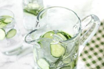 Refreshing cucumber water with rosemary in jug on table, closeup