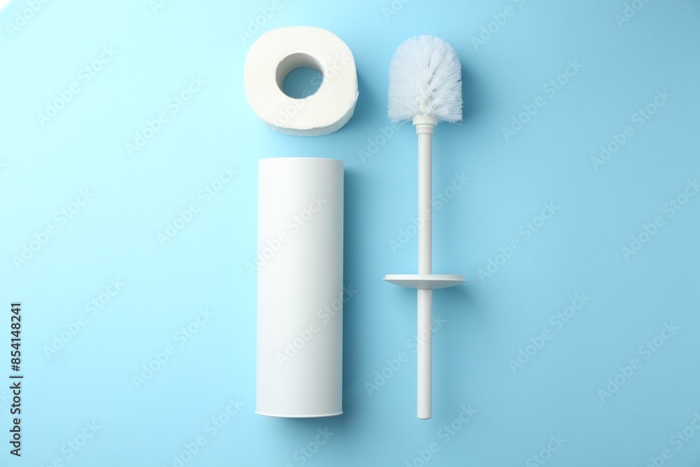 Wall mural Toilet brush, roll of paper and holder on light blue background, flat lay