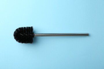 Toilet brush on light blue background, top view