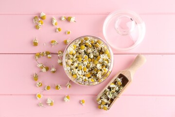 Chamomile flowers in glass jar and scoop on pink wooden table, flat lay