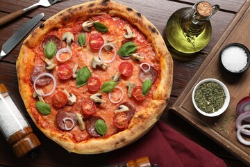 Delicious pizza with salami, vegetables, mushrooms and basil served on wooden table, flat lay