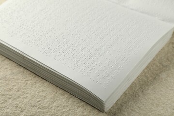 Book with Braille text on beige textured table, closeup. Education and leisure for blind people