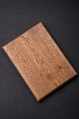 Empty wooden cutting board on dark textured concrete background