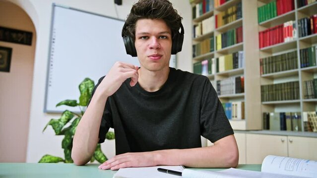 Web cam portrait of college student guy in headphones looking talking to camera