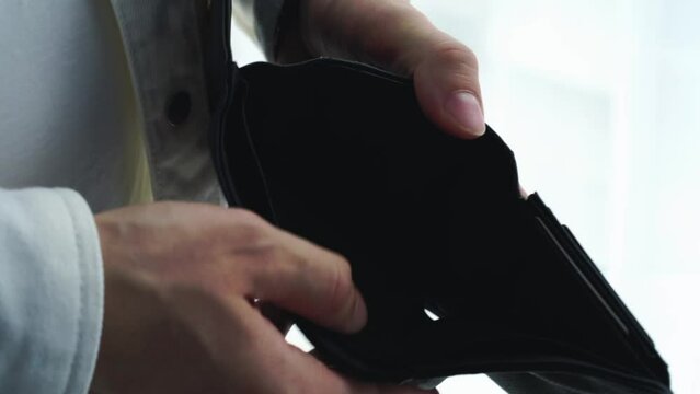 man with an empty wallet.
A man holds an empty wallet in his hands.