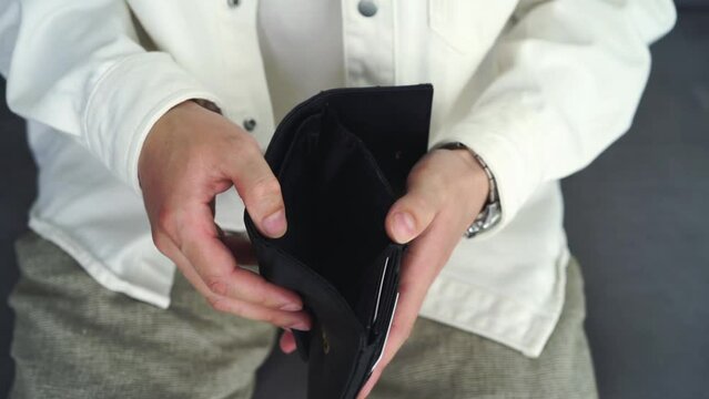 man with an empty wallet.
A man holds an empty wallet in his hands.