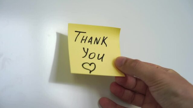 A man puts a sticker on his refrigerator that says THANK YOU.
The man in the note thanks.
Sticker on the refrigerator.
Thanking a person