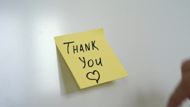 A man puts a sticker on his refrigerator that says THANK YOU.
The man in the note thanks.
Sticker on the refrigerator.
Thanking a person