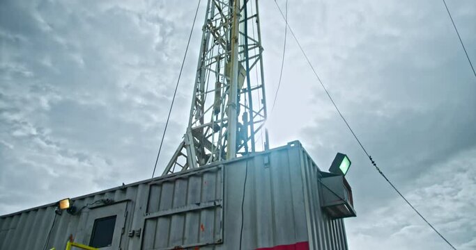 Cabin for work staff at the site for gas or oil production. Rig tower for drilling is at backdrop. Low angle view.