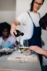 Close up of hand pouring wine in wineglass on pottery class.