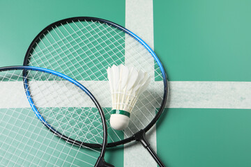 Feather badminton shuttlecocks and rackets on green table, above view