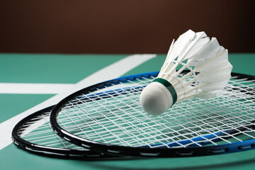 Feather badminton shuttlecock and rackets on court, closeup