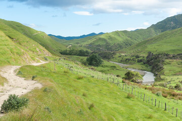 Fototapeta premium Dirt track and fence-line along hillside following river below in valley