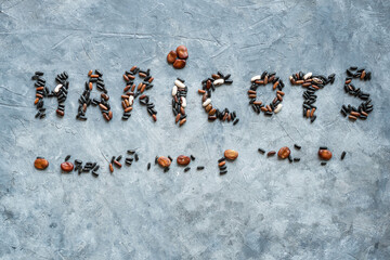 French word HARICOTS (meaning Beans) is laid out on a grey background of dried beans seeds. View from above